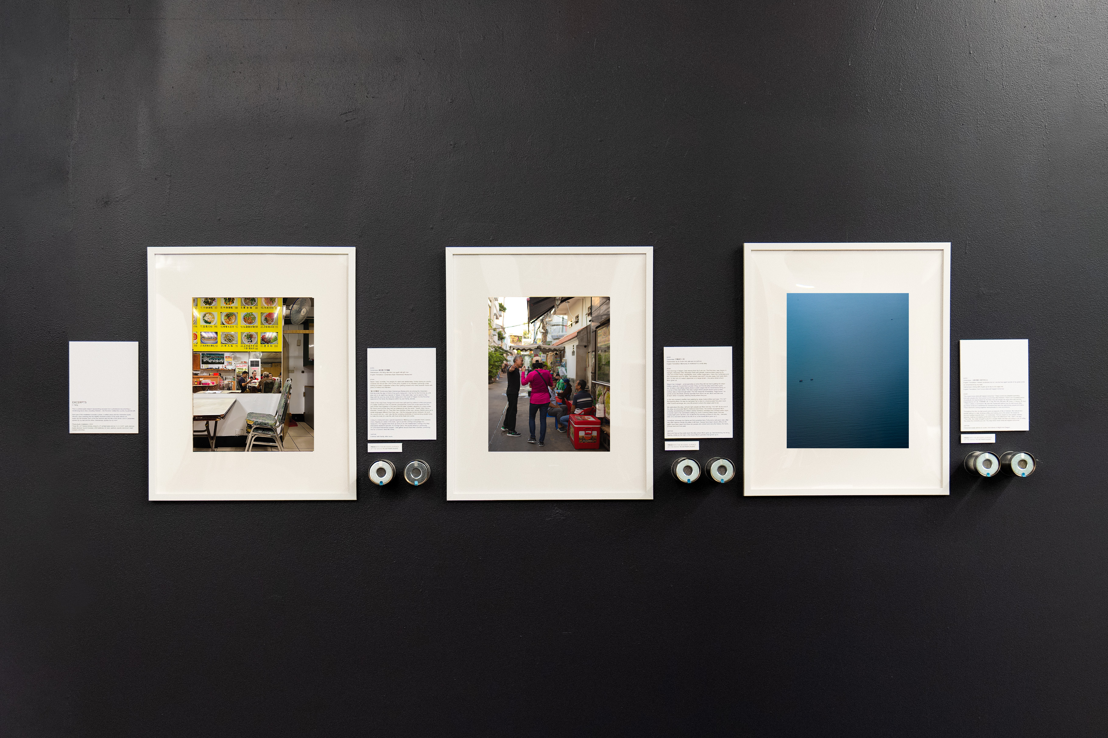 Image of 'Excerpts' photo-audio installation with three framed photos on wall with a piece of writing and two audio tin cans next to each photo